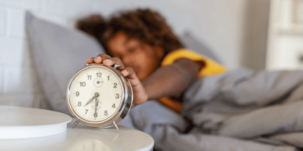 young woman snoozing alarm clock