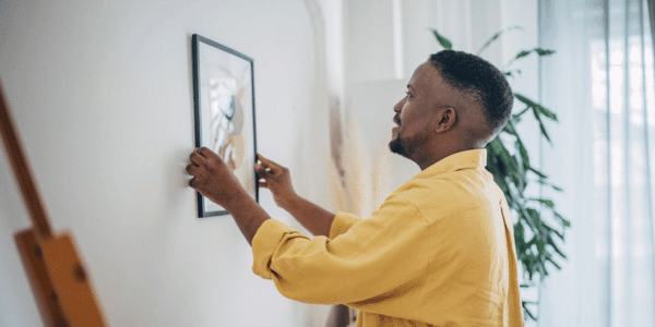 man hanging gallery wall photo in home