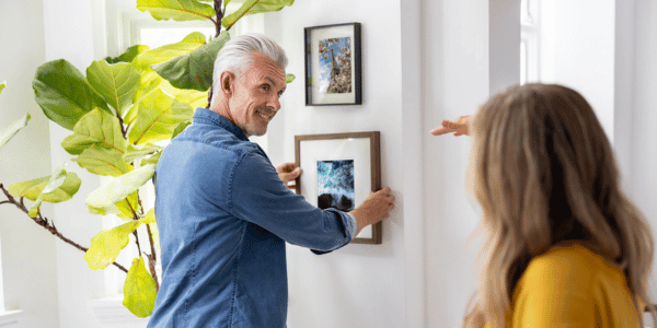 man and woman hanging photos for gallery wall in living room