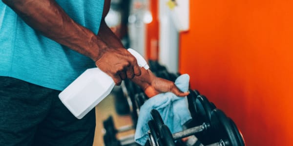 man following gym rules and wiping down weights