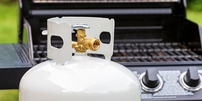 Detached propane tank in front of open grill