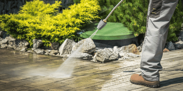 man pressure washing patio
