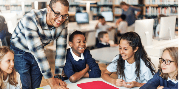 male teacher talking to four students after receiving teach gift