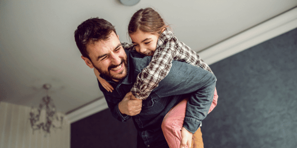 child riding father's back after hearing dad joke
