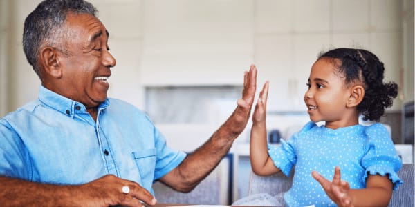 grandfather and granddaughter high-fiving after telling dad jokes