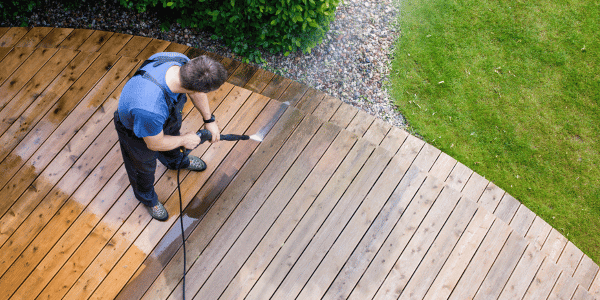 person using pressure washer to clean deck