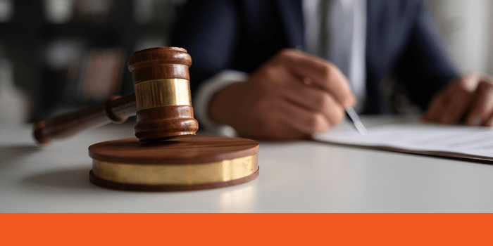 Gavel on sound block with man in suit writing in the background