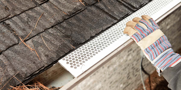 person doing gutter maintenance and installing gutter guards