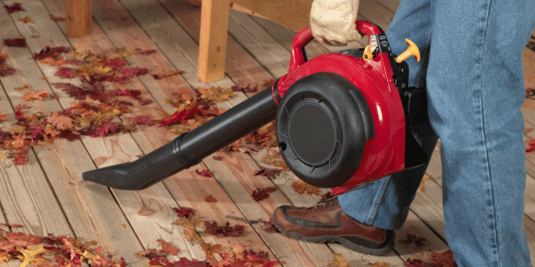 person using leaf blower to clean fall leaves
