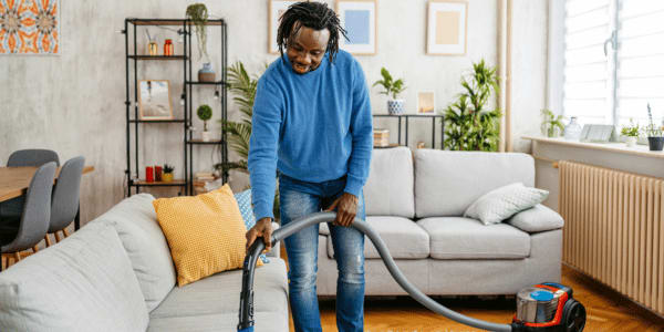man cleaning couch to make house smell good