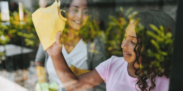 mother and daughter cleaning windows in home