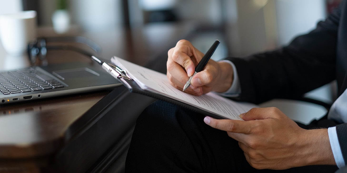 Businessman filling out document on clipboard
