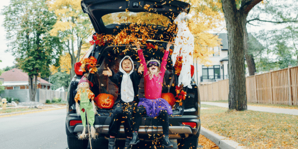 two children in Halloween costumes in trunk of car for trunk or treat