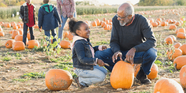 grandfather and granddaughter picking out pumpkins at pumpkin patch