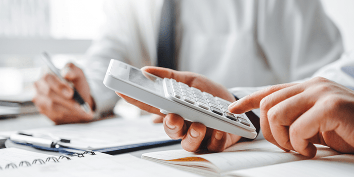 Businessmen sitting using calculator and writing on clipboard