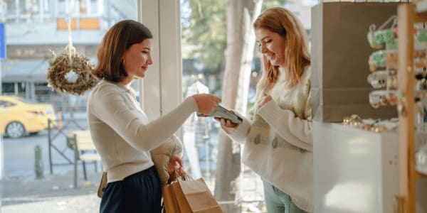 Young female customer paying in a vintage clothing shop on Small Business Saturday