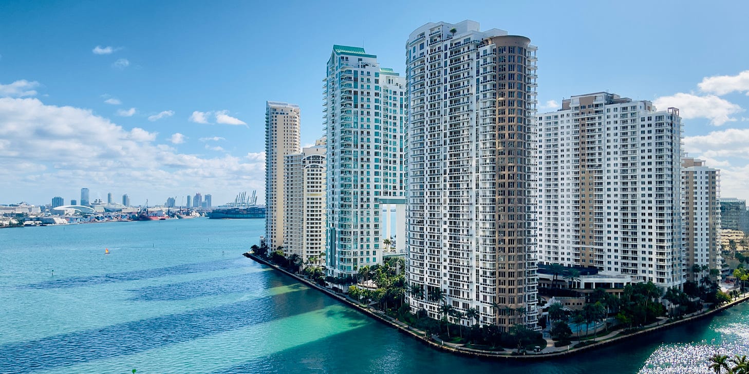 Brickell neighborhood in Miami, FL with city skyline and high-rises surrounded by the ocean.