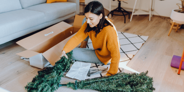 young woman taking apart fake Christmas tree