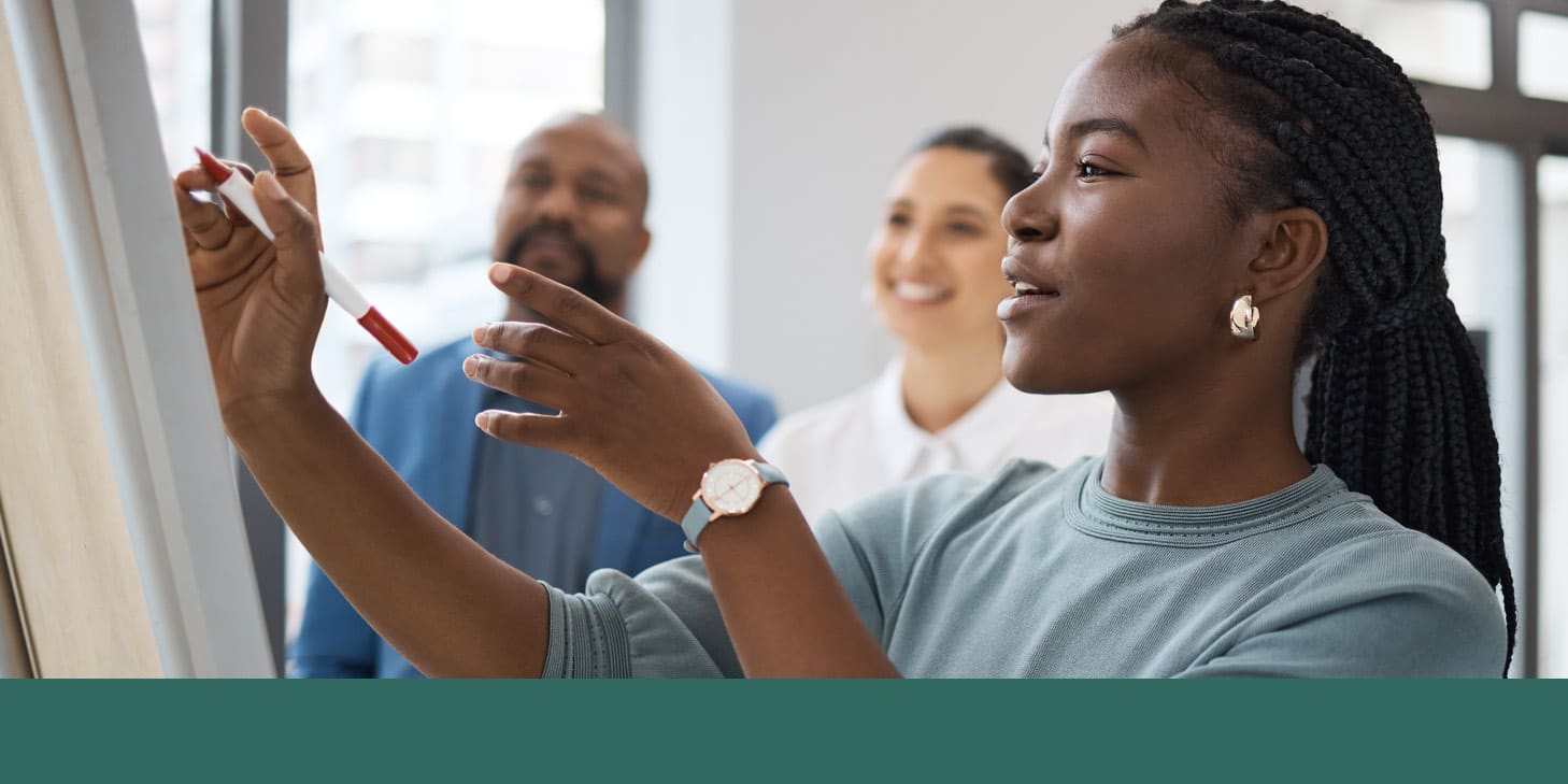 Three board members outlining goals on a whiteboard using a red marker.