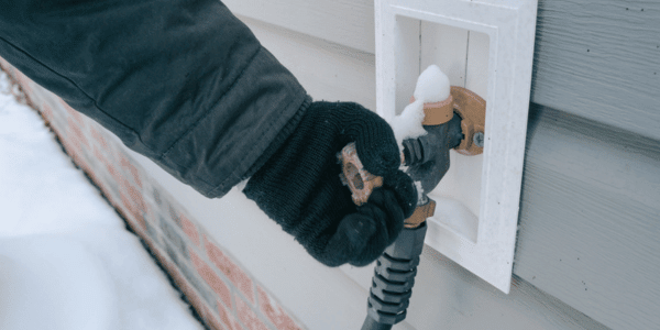 woman checking frozen outdoor pipe