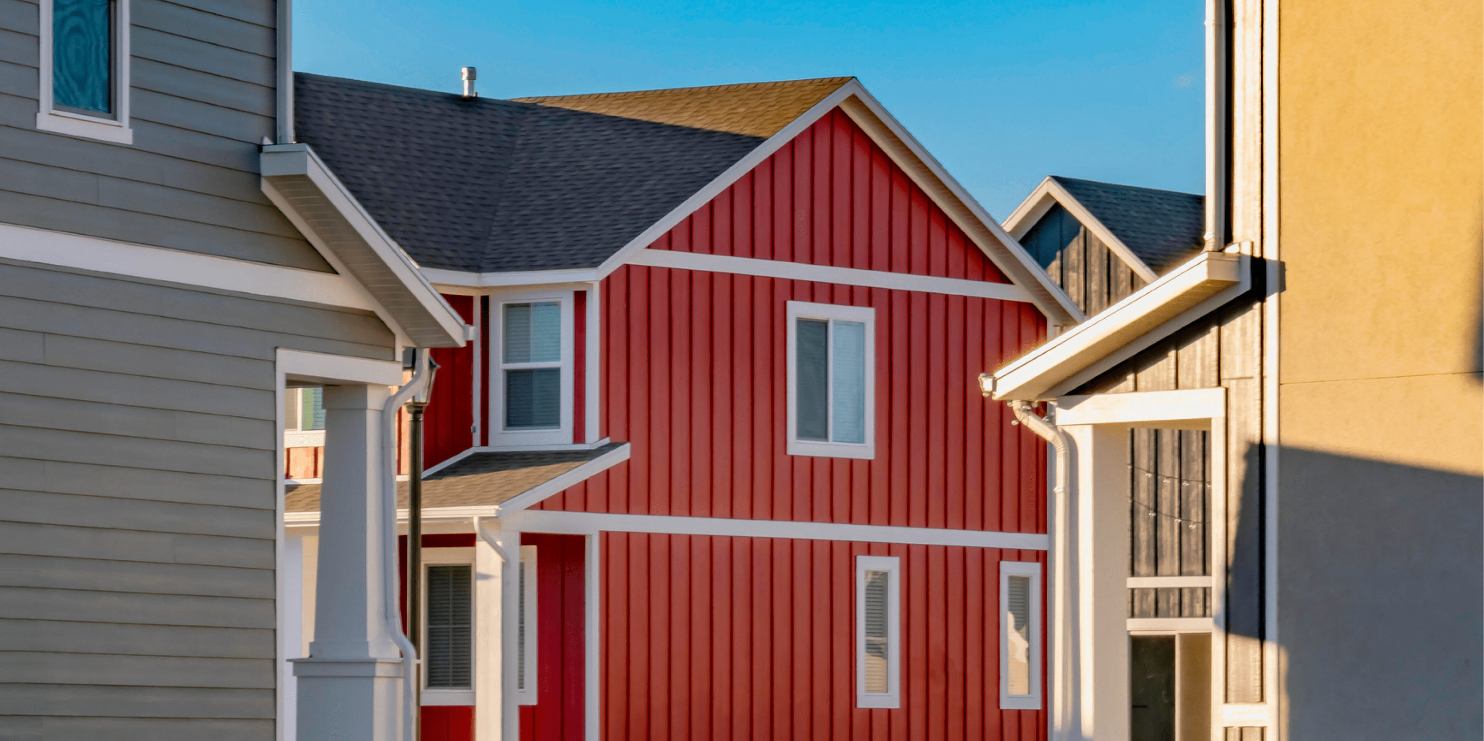 Row of two-story homes painted grey, red, and black with white outlines.