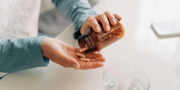 woman pouring vitamins in hand