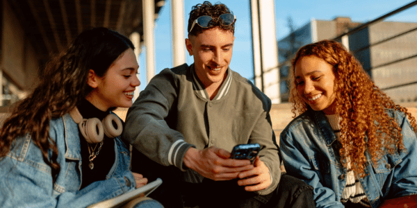 three Gen Z students looking at cellphone