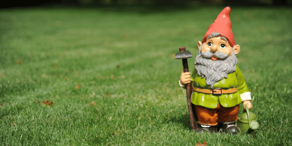 Close-up of garden gnome holding pickax and watering can 