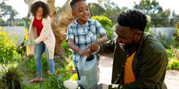 happy family watering plants in their spring garden