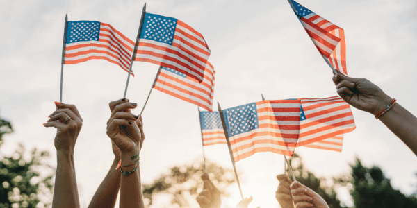 group of people waving American flags at sunset on Flag Day
