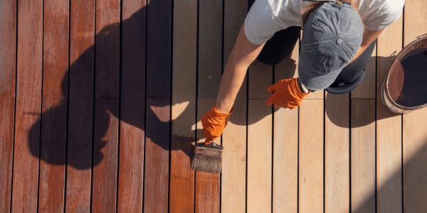 man applying stain to deck