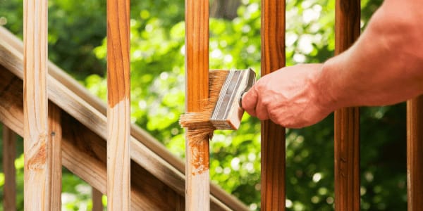 man applying stain to deck spindles 