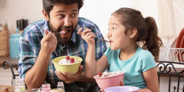father and daughter eating ice cream sundaes 