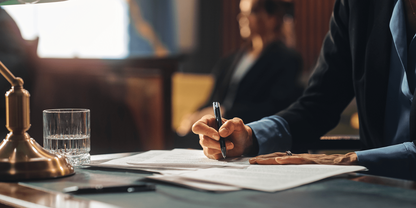 Close up of a lawyer's hands writing on a legal document with a pen