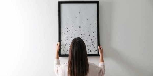 woman hanging picture on wall