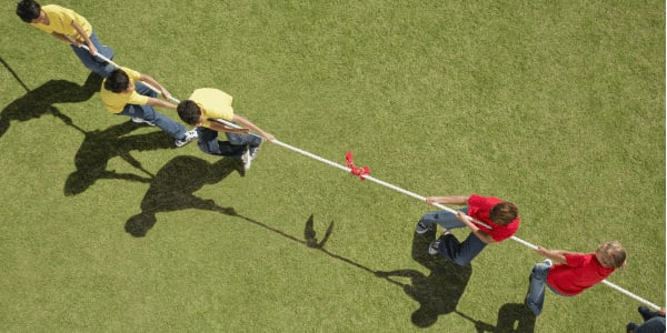 group of children playing tug-of-war game in backyard