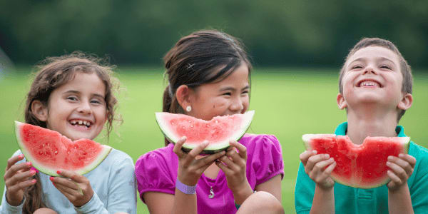 three young children eating watermelon slices