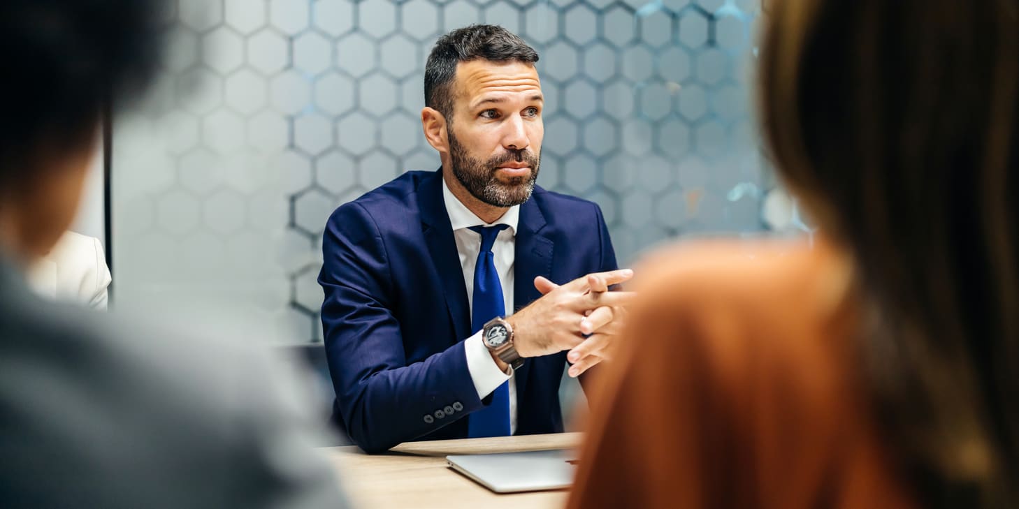 Focused businessman speaking to colleagues sitting across from him in a meeting.