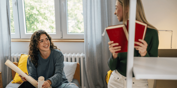 two girls sitting in dorm room and unpacking for college