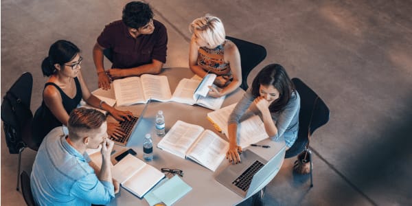 group of college students studying at circular table in library