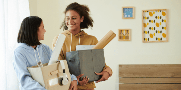 two college women holding dorm moving boxes