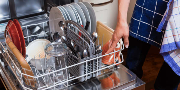 woman emptying dishwasher full of kitchen supplies
