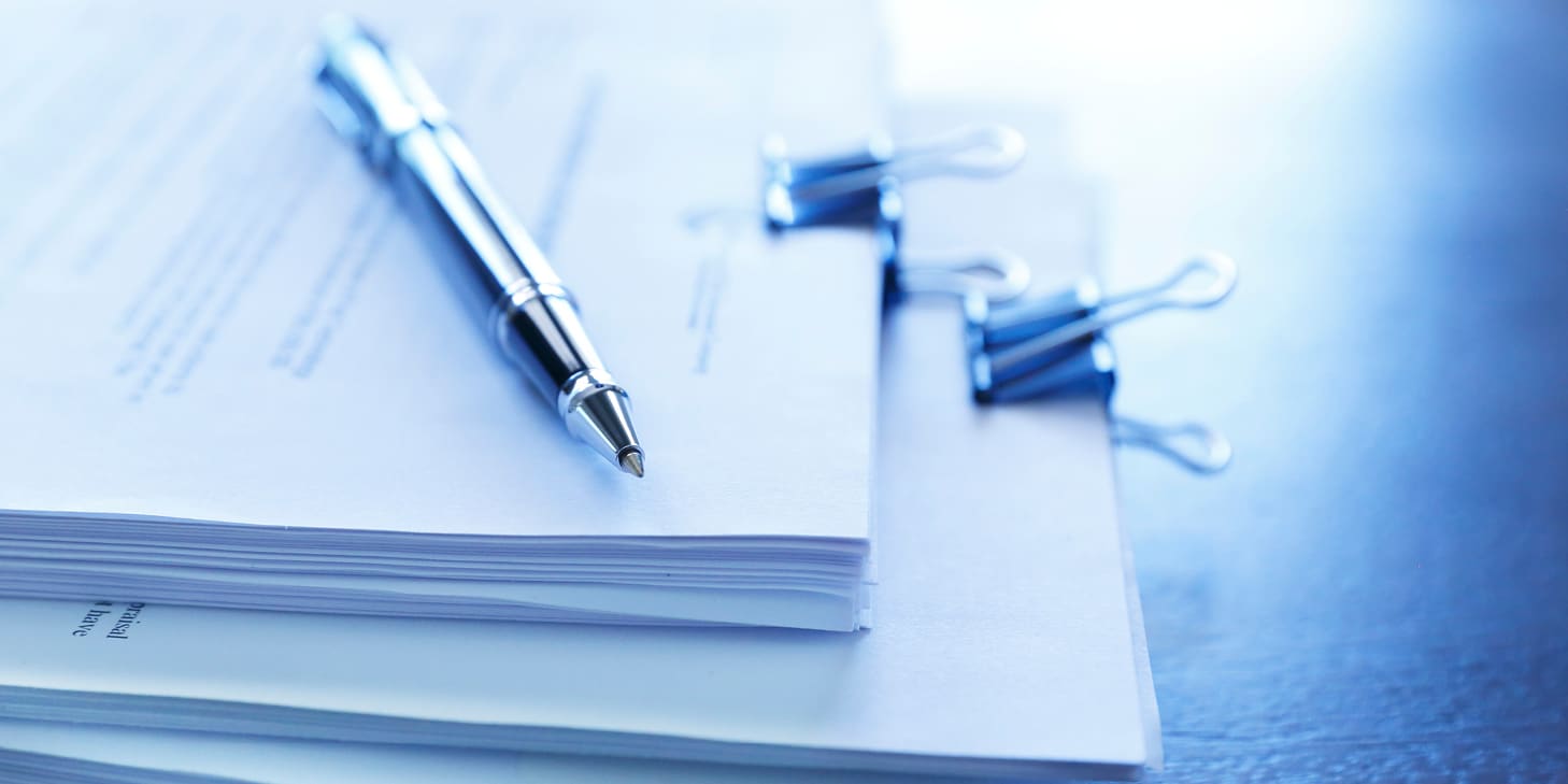 Ballpoint pen resting on top of a stack of documents
