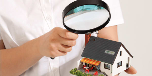 person holding magnifying glass over home after home inspection