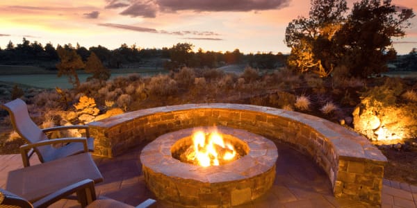 built-in backyard fire pit surrounded by stone ledge