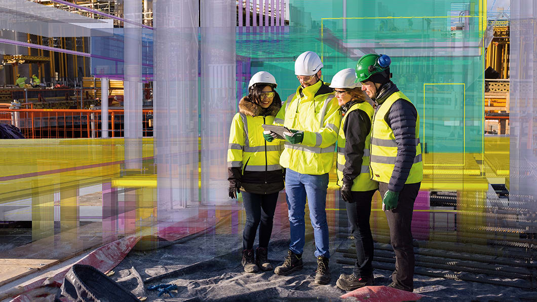 Four construction professionals wearing safety gear and high-visibility jackets examine a tablet on a construction site, overlaid with a transparent digital 3D model representing Building Information Modeling (BIM) technology.
