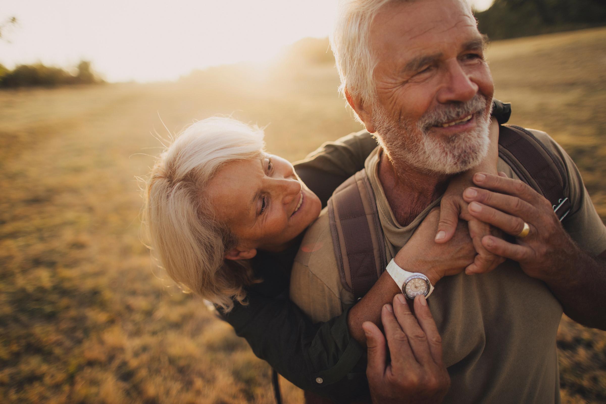 A senior couple embrace in a sunny field