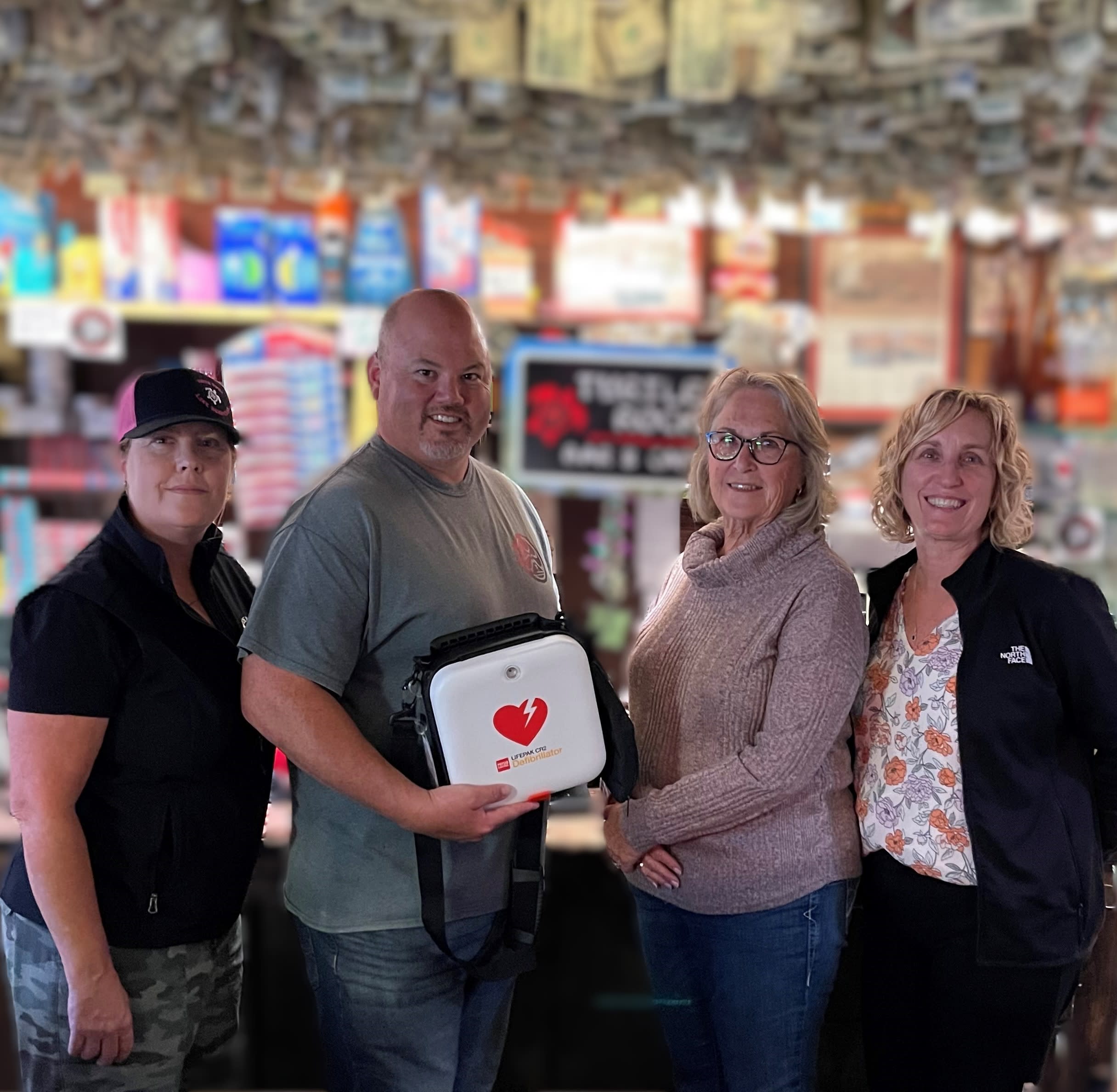 Turtle Rock Bar & Cafe employee, Brooke Baraz (far left) and owner, Pete Leung (center left) stand next to Janice Casey (center right) and Michele White, manager of risk management (far right). Pete holds the AED donated by Providence Queen of the Valley Foundation following the incident.