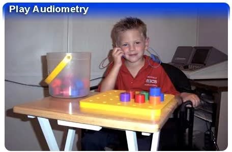 Child with earbuds playing with toys on a table.