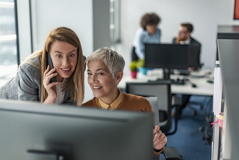 Two people working together and looking on to a screen